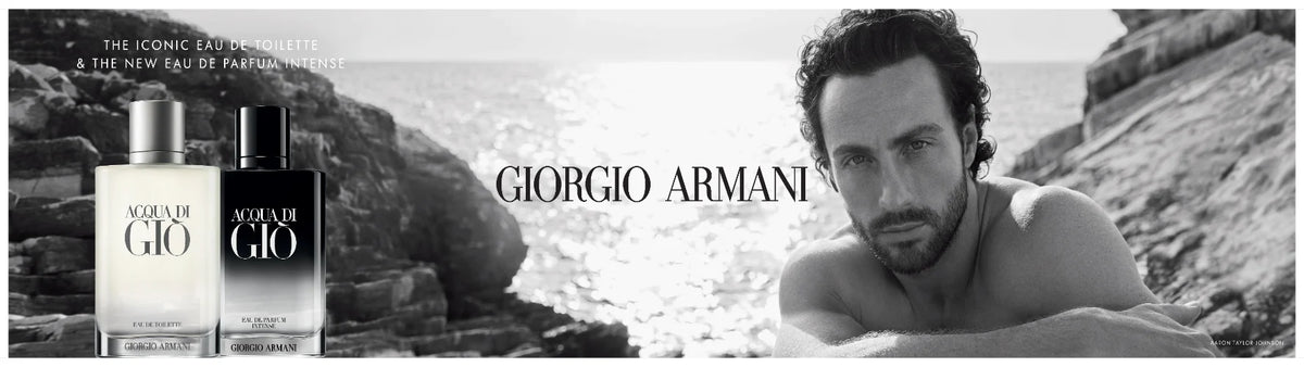 Acqua di Giò Elixir perfume bottle on a white stone surface by the sea with grey sky